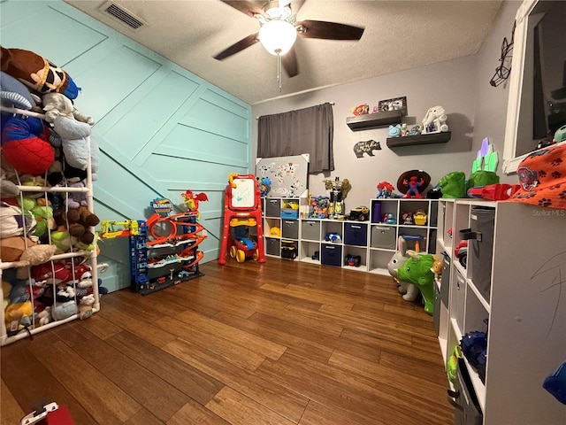 recreation room with hardwood / wood-style floors, a textured ceiling, and ceiling fan