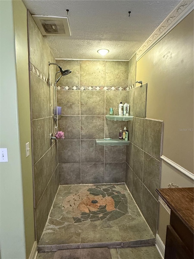 bathroom featuring vanity, a tile shower, and a textured ceiling