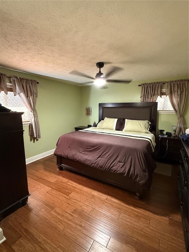 bedroom featuring multiple windows, a textured ceiling, light hardwood / wood-style floors, and ceiling fan