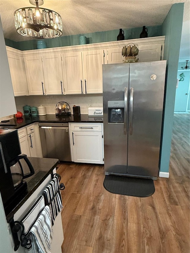 kitchen featuring hardwood / wood-style floors, white cabinetry, appliances with stainless steel finishes, and pendant lighting