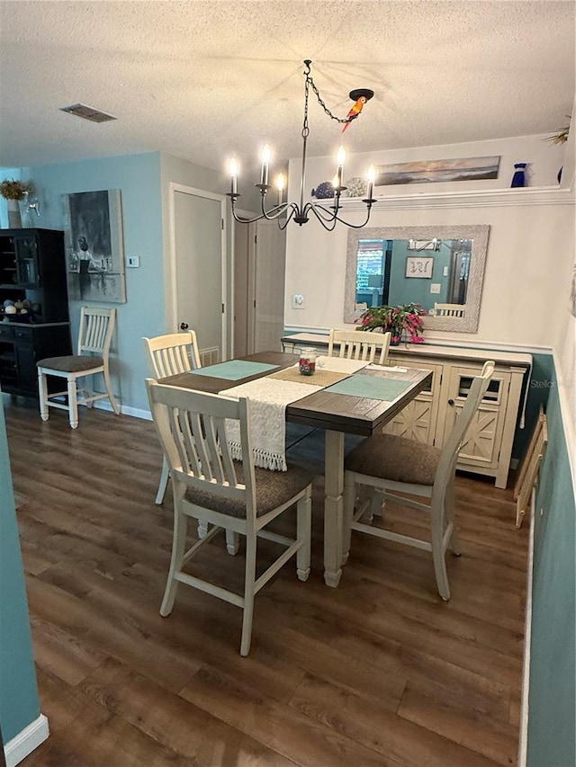 dining space with a textured ceiling, a notable chandelier, and dark hardwood / wood-style flooring