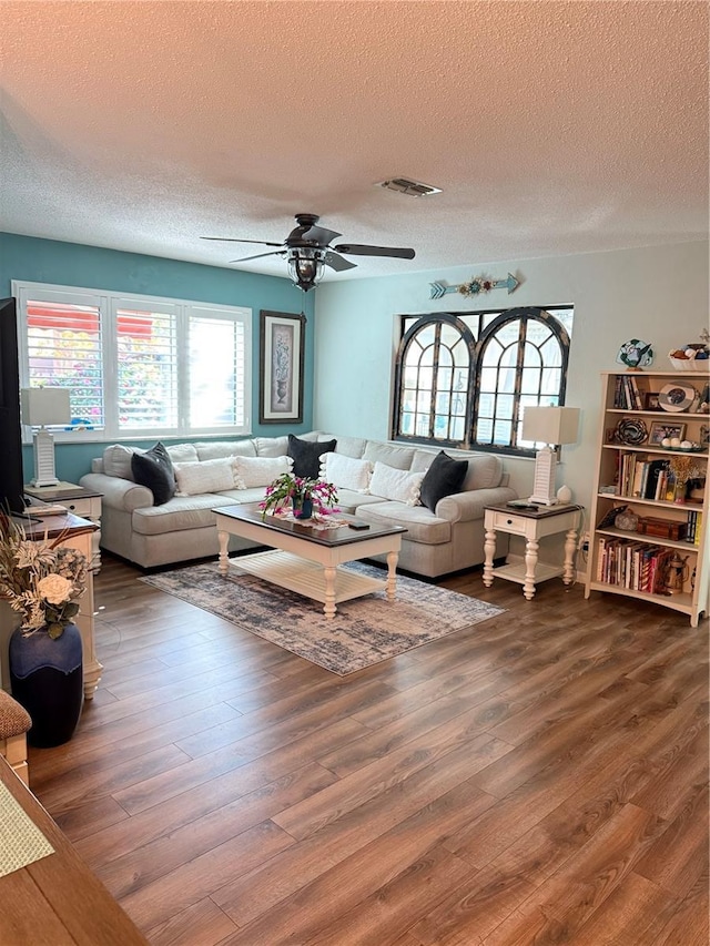 living room with hardwood / wood-style floors, a textured ceiling, and ceiling fan