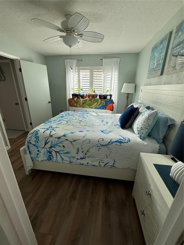 bedroom with ceiling fan, dark hardwood / wood-style floors, and a textured ceiling