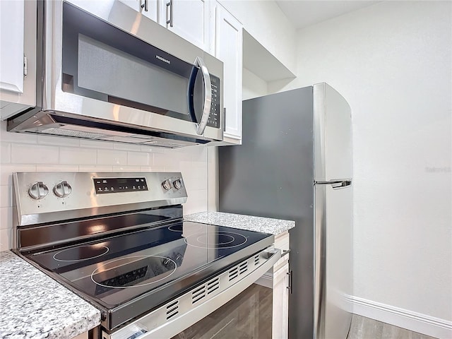 kitchen featuring white cabinets, light wood-type flooring, backsplash, and stainless steel appliances