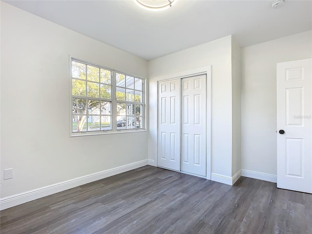 unfurnished bedroom with dark hardwood / wood-style flooring and a closet