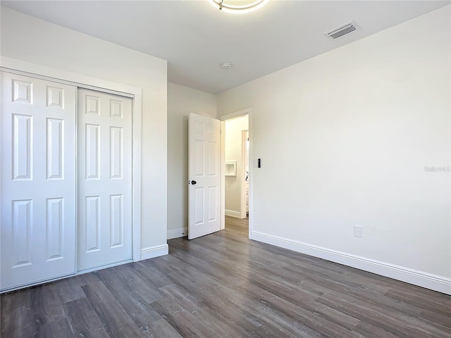 unfurnished bedroom featuring a closet and dark hardwood / wood-style floors