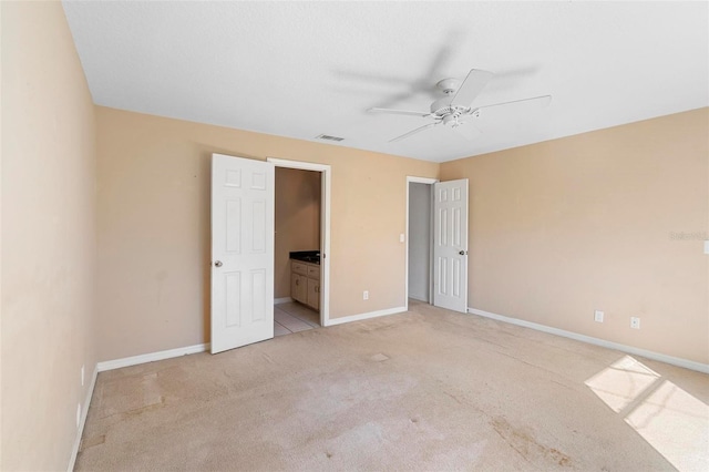 unfurnished bedroom with connected bathroom, ceiling fan, and light colored carpet