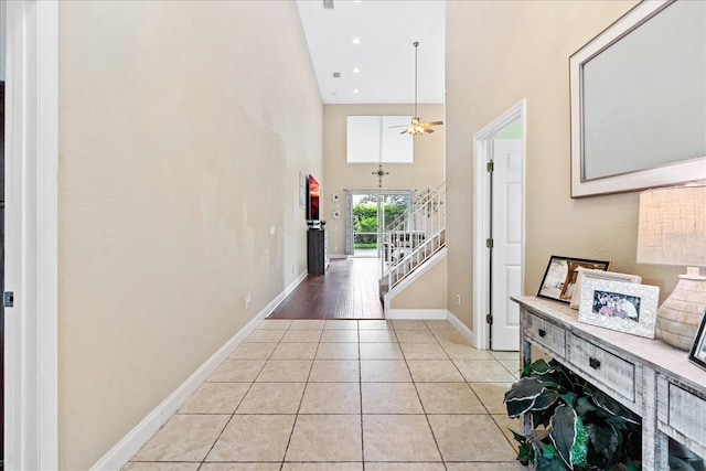 hallway featuring light tile patterned floors and a towering ceiling