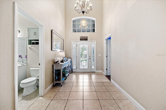 tiled entryway with a towering ceiling and a chandelier