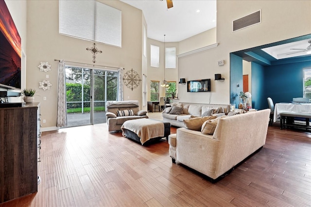 living room with ceiling fan, hardwood / wood-style floors, and a towering ceiling