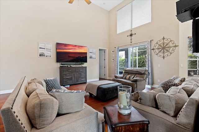 living room featuring ceiling fan, dark wood-type flooring, and a high ceiling