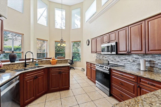 kitchen with sink, a high ceiling, a notable chandelier, pendant lighting, and appliances with stainless steel finishes