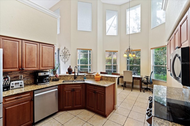 kitchen featuring stainless steel appliances, sink, an inviting chandelier, a high ceiling, and hanging light fixtures