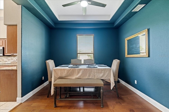 dining room featuring a tray ceiling, ceiling fan, and hardwood / wood-style flooring