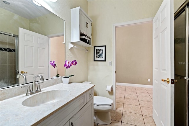 bathroom featuring tile patterned floors, toilet, vanity, and walk in shower