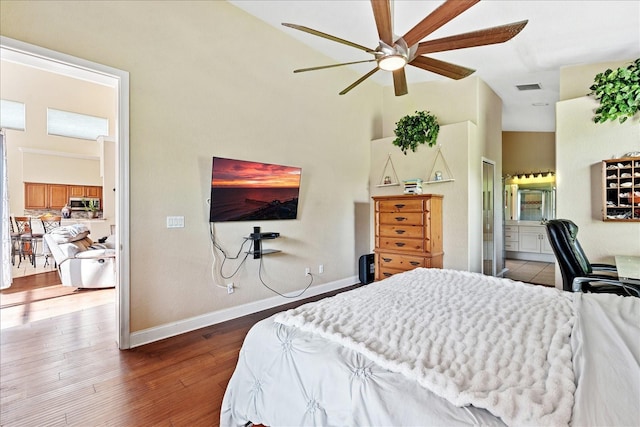 bedroom with ceiling fan, dark hardwood / wood-style flooring, a towering ceiling, and ensuite bath