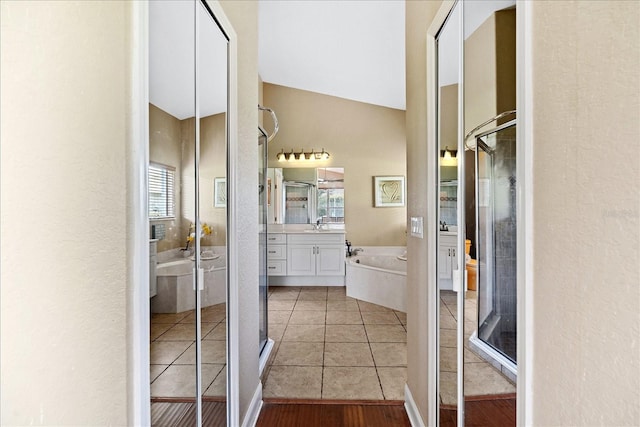 bathroom with a bathtub, tile patterned flooring, vanity, and vaulted ceiling