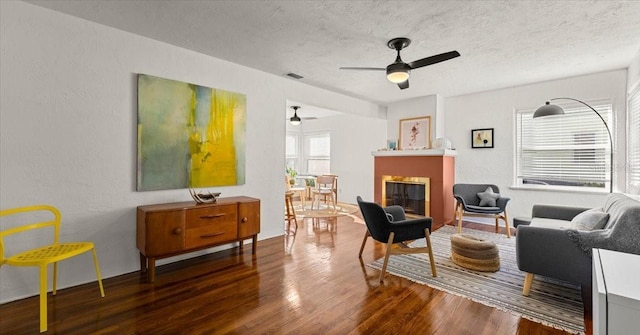 living room with a textured ceiling, dark hardwood / wood-style flooring, and ceiling fan