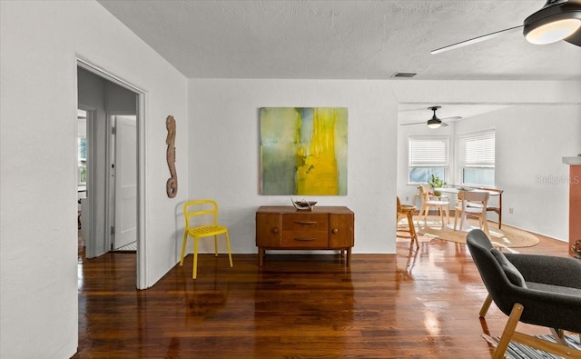 sitting room featuring ceiling fan, dark hardwood / wood-style floors, a textured ceiling, and a wealth of natural light