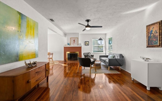 sitting room with a textured ceiling, ceiling fan, and dark wood-type flooring