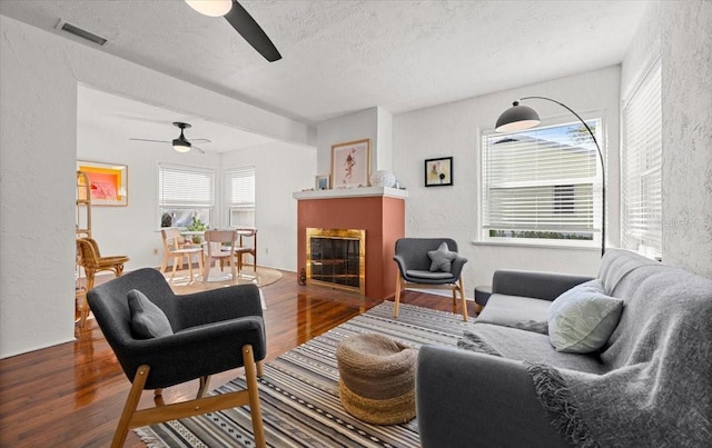 living room featuring a textured ceiling, dark hardwood / wood-style floors, and ceiling fan