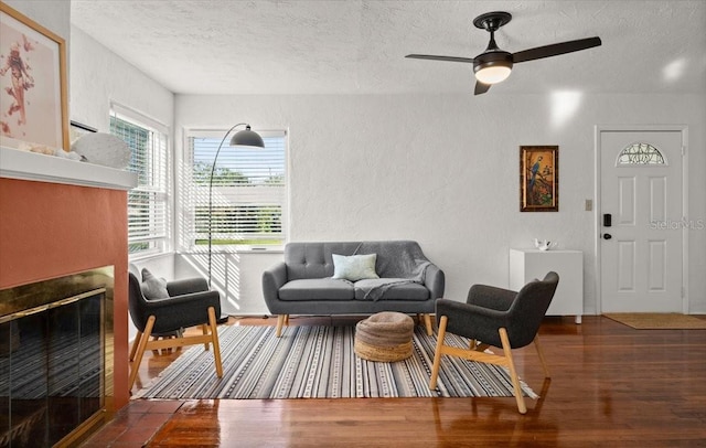 living room featuring ceiling fan, dark hardwood / wood-style floors, and a textured ceiling