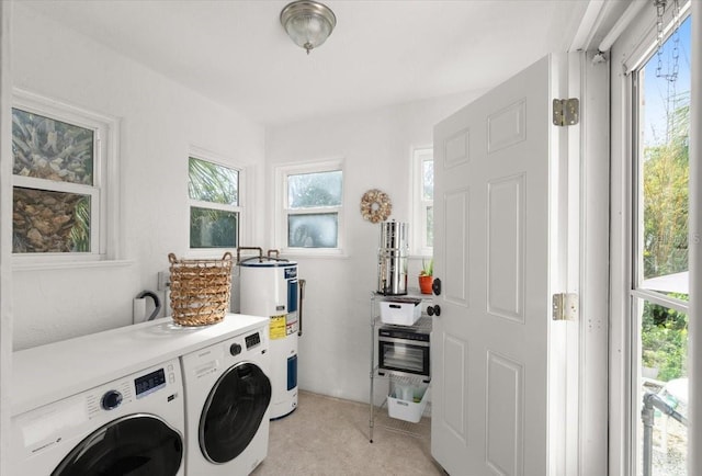 clothes washing area featuring a wealth of natural light, water heater, and washer and clothes dryer