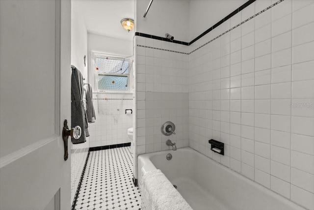 bathroom featuring tiled shower / bath combo and toilet