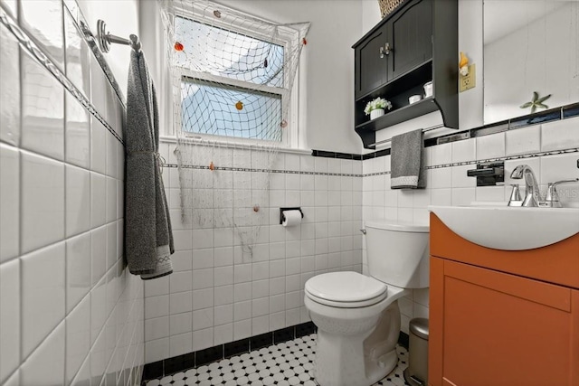 bathroom featuring tile patterned flooring, vanity, toilet, and tile walls