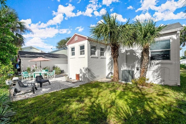 rear view of property with a lawn, central AC unit, and a patio area