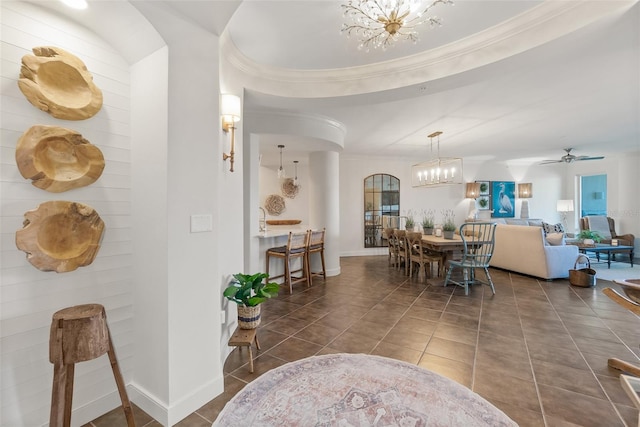 tiled dining room with ceiling fan with notable chandelier, a raised ceiling, and crown molding