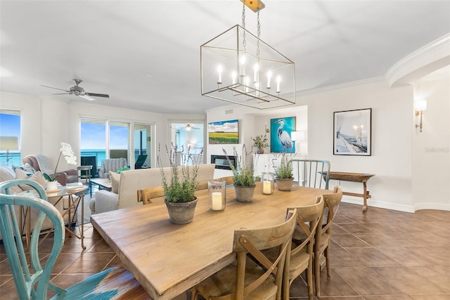 tiled dining room with a water view, ceiling fan, and crown molding