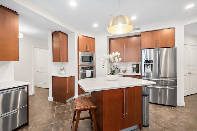 kitchen with pendant lighting, a center island, dark tile patterned floors, tasteful backsplash, and stainless steel appliances