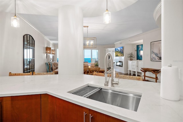 kitchen with hanging light fixtures, crown molding, and sink