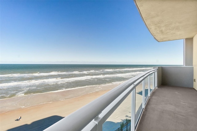 balcony featuring a view of the beach and a water view