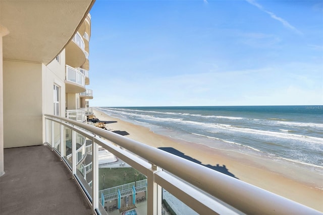 balcony featuring a view of the beach and a water view