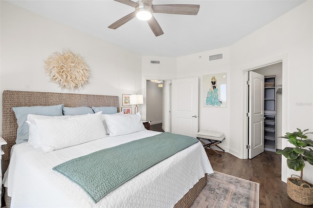 bedroom with a closet, a spacious closet, dark hardwood / wood-style flooring, and ceiling fan