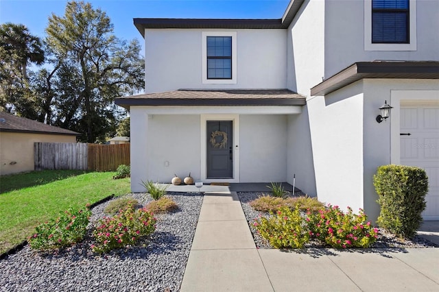 entrance to property with a garage and a lawn