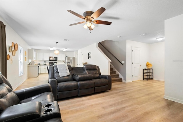 living room featuring ceiling fan and light wood-type flooring