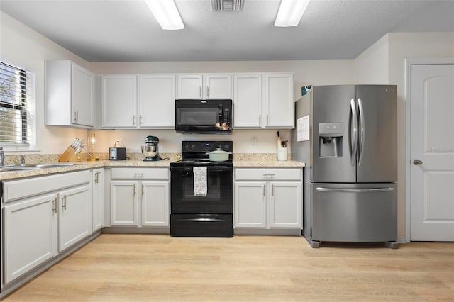 kitchen featuring sink, light wood-type flooring, white cabinetry, and black appliances