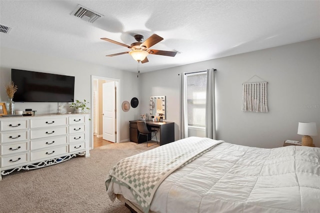 bedroom featuring a textured ceiling, light colored carpet, and ceiling fan