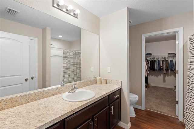 bathroom with a shower with curtain, a textured ceiling, vanity, hardwood / wood-style flooring, and toilet