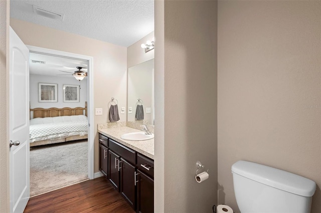 bathroom featuring ceiling fan, hardwood / wood-style floors, a textured ceiling, toilet, and vanity