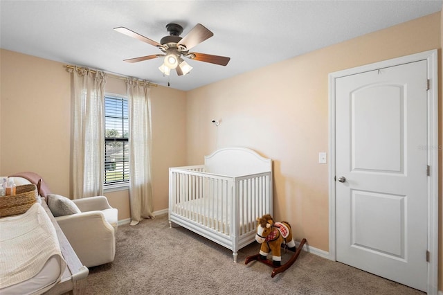 bedroom with ceiling fan, a crib, and light carpet