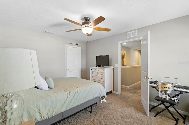 bedroom with ceiling fan, light colored carpet, and a textured ceiling