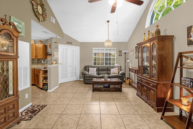 tiled living room with ceiling fan with notable chandelier, high vaulted ceiling, and sink