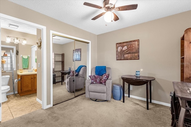 living area with a textured ceiling, ceiling fan, and light carpet