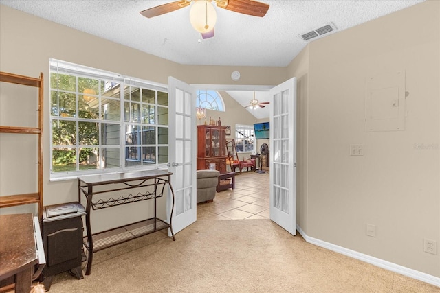 interior space with a textured ceiling, lofted ceiling, french doors, and plenty of natural light