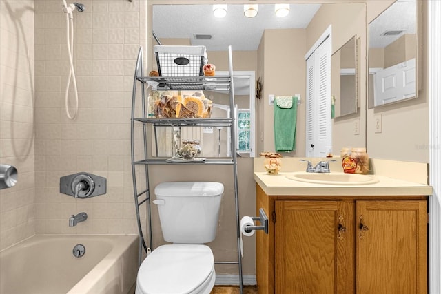 full bathroom with tiled shower / bath, vanity, a textured ceiling, and toilet