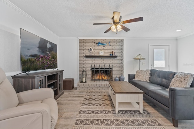 living room with a fireplace, a textured ceiling, ceiling fan, and crown molding